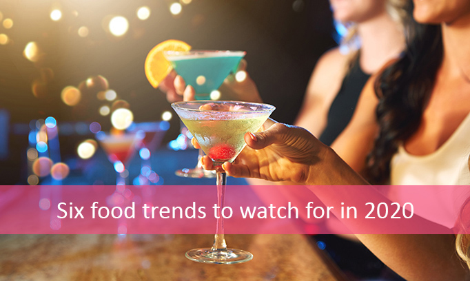 Three women at a bar drinking colorful martinis to celebrate the New Year.